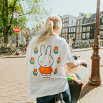 Mujer con la camiseta blanca de lactancia Miffy, con un tulipán bordado y cremalleras para la lactancia